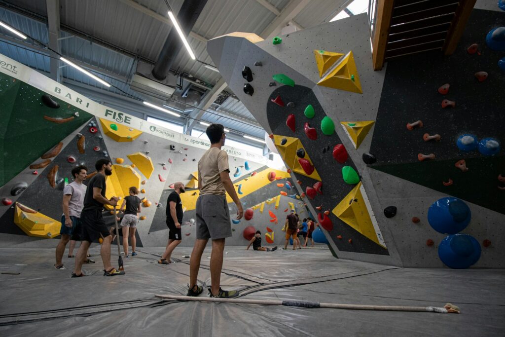 People gathered around a climbing wall while a climber studies the route ahead