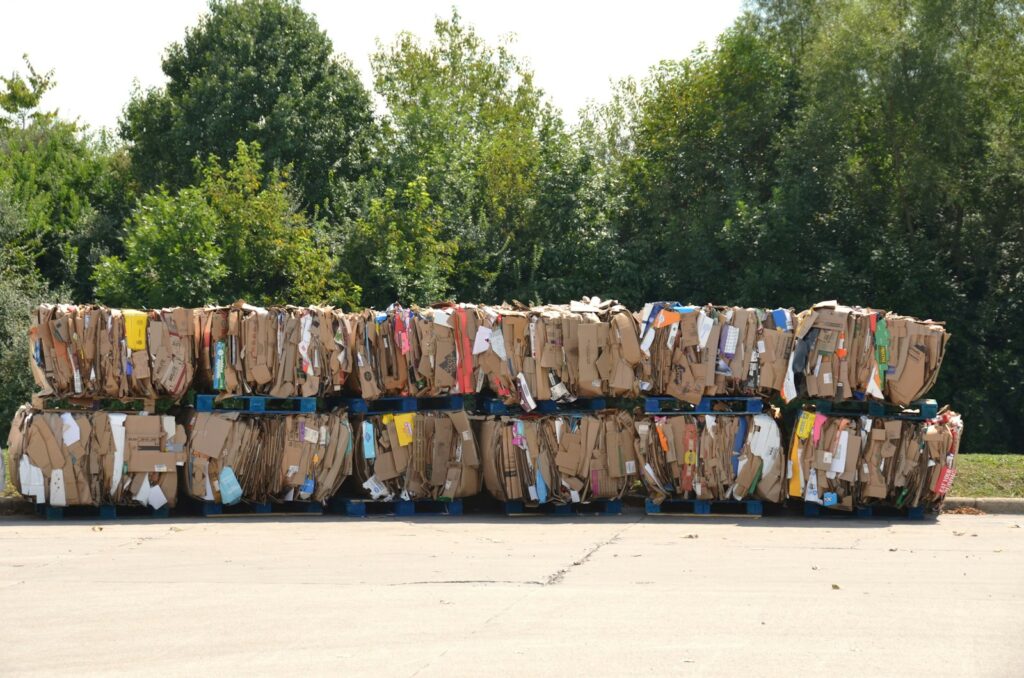 Stacked bales of compressed cardboard on blue pallets, waiting to be collected for recycling