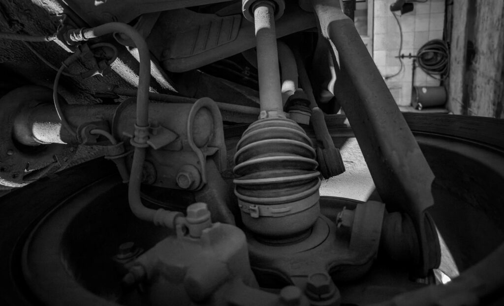 Close-up of a car's underside showing suspension and steering components in a repair workshop