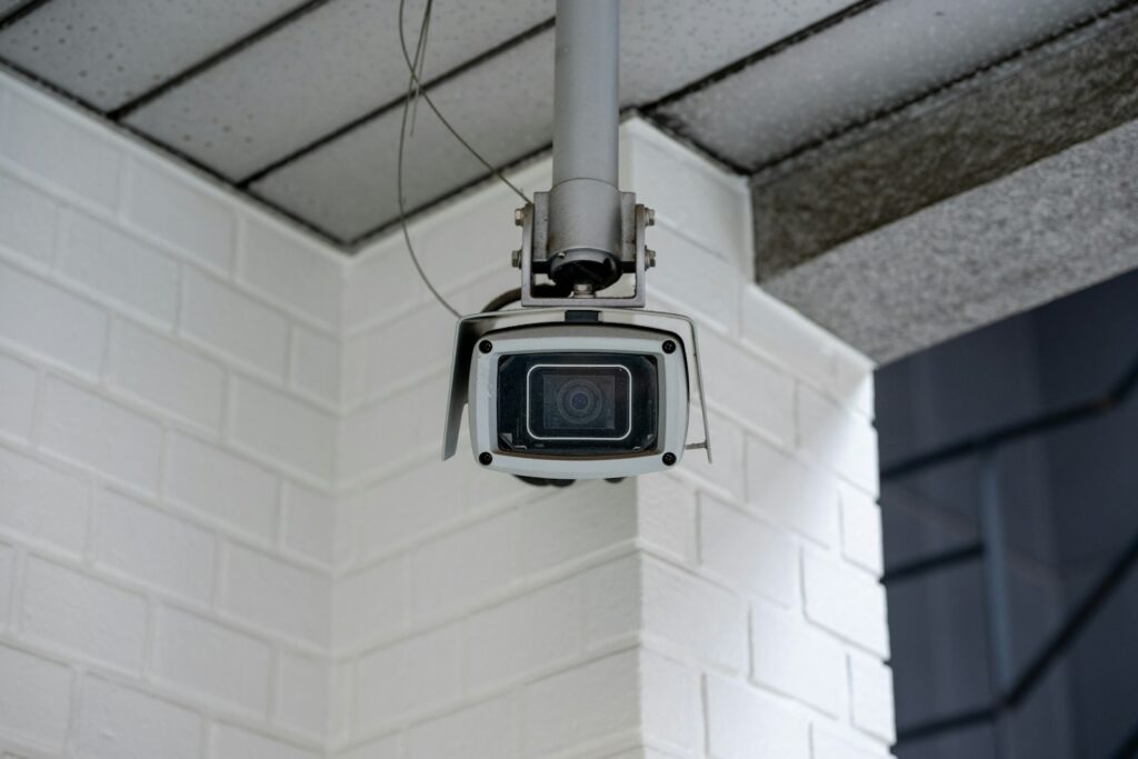 Security camera mounted on a white brick wall, the kind that needs regular checking