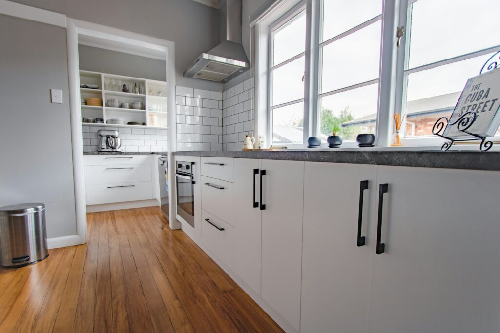 White kitchen cabinets with black handles in a simple, bright kitchen