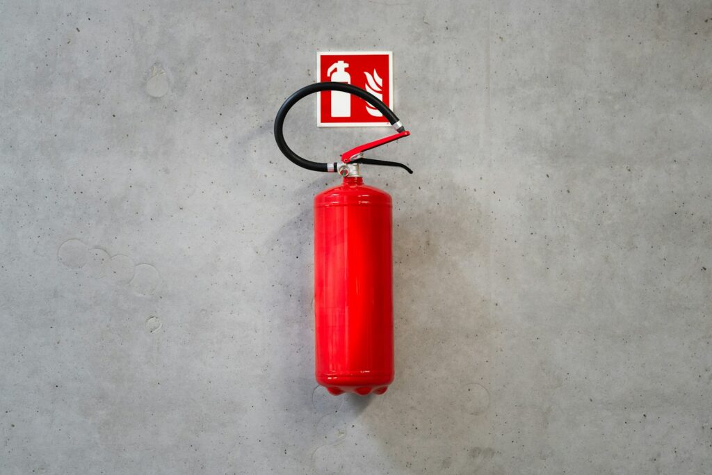 Red fire extinguisher hanging on a wall, part of a building's fire safety equipment
