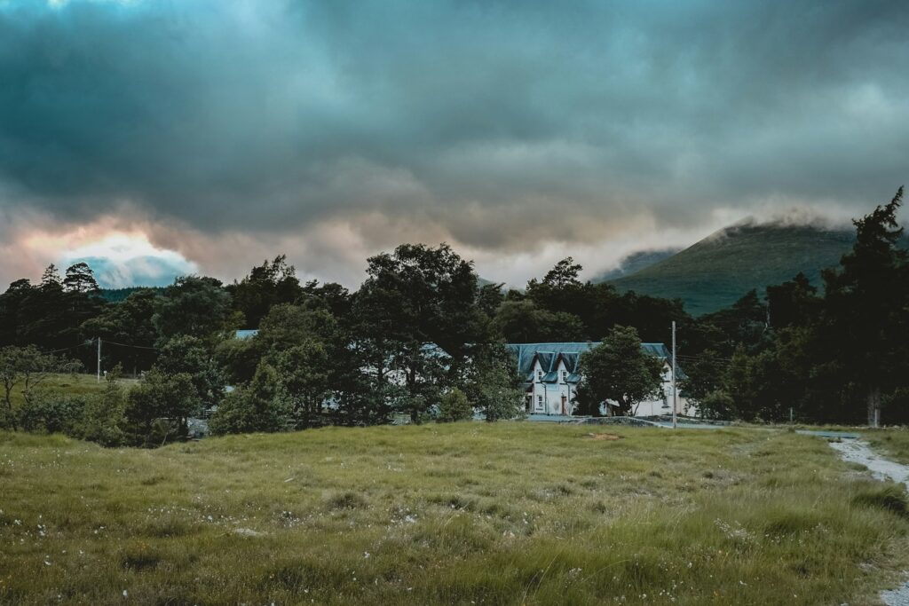 Remote hotel standing in a field with mountains behind, in the Scottish Highlands